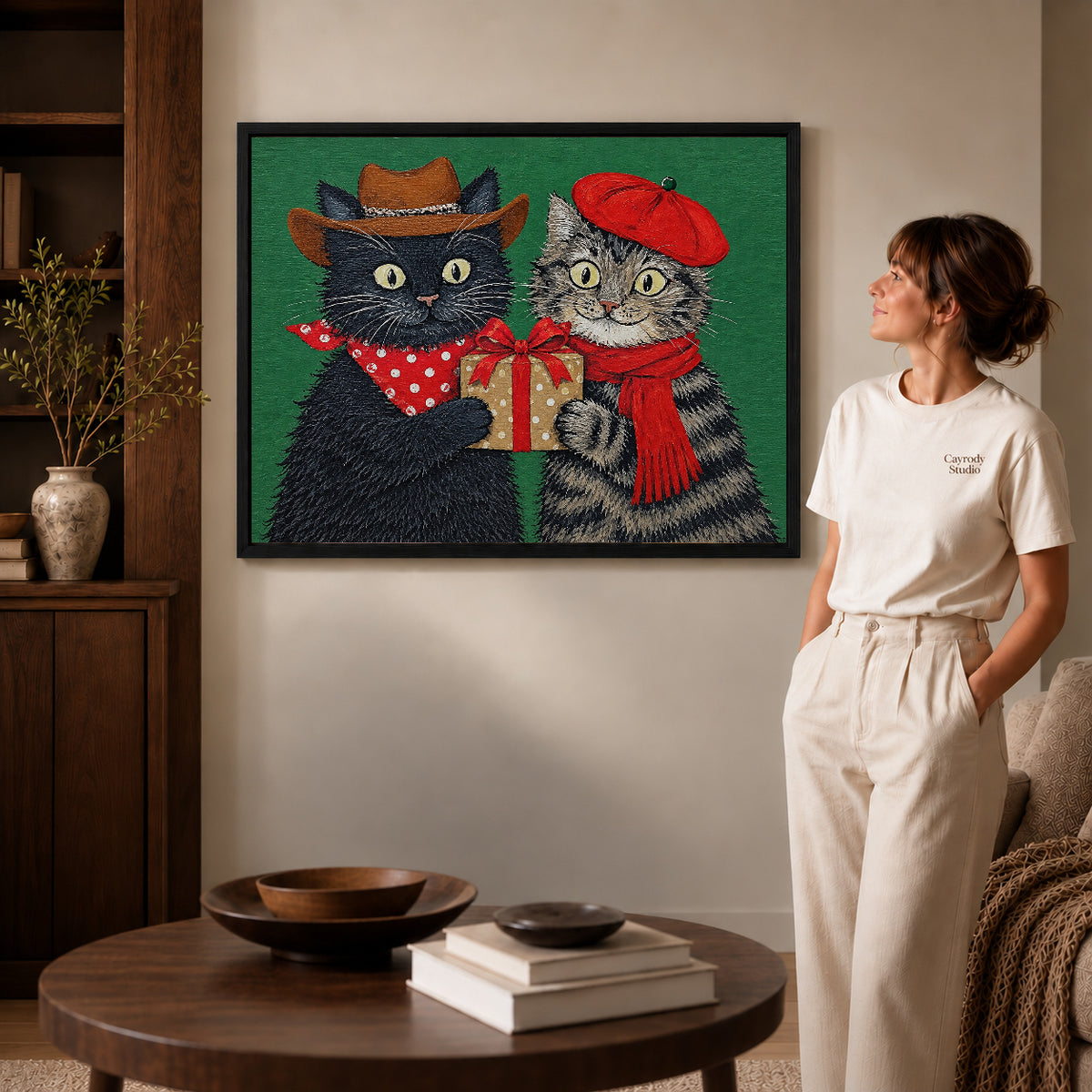 Holiday Gift Cats canvas art in a black frame above books in a welcoming living room.