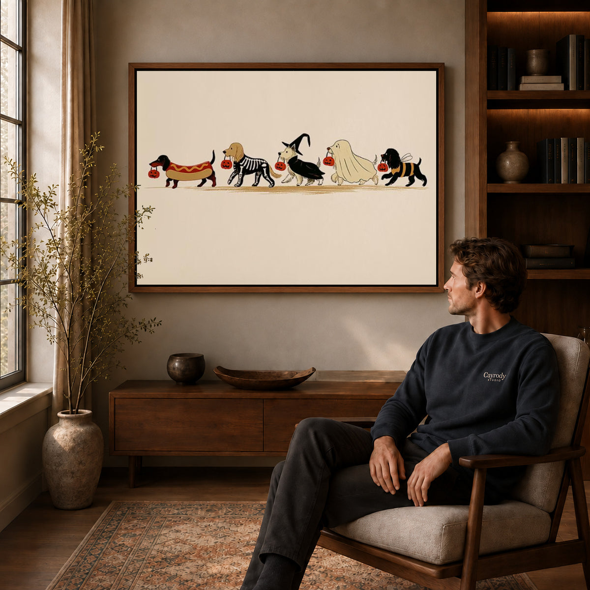 Costumed Dog Parade canvas art above a wooden console beside a seated man in a warm room.