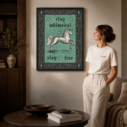 Black framed free spirit unicorn canvas art displayed beside a woman in a warm living room.