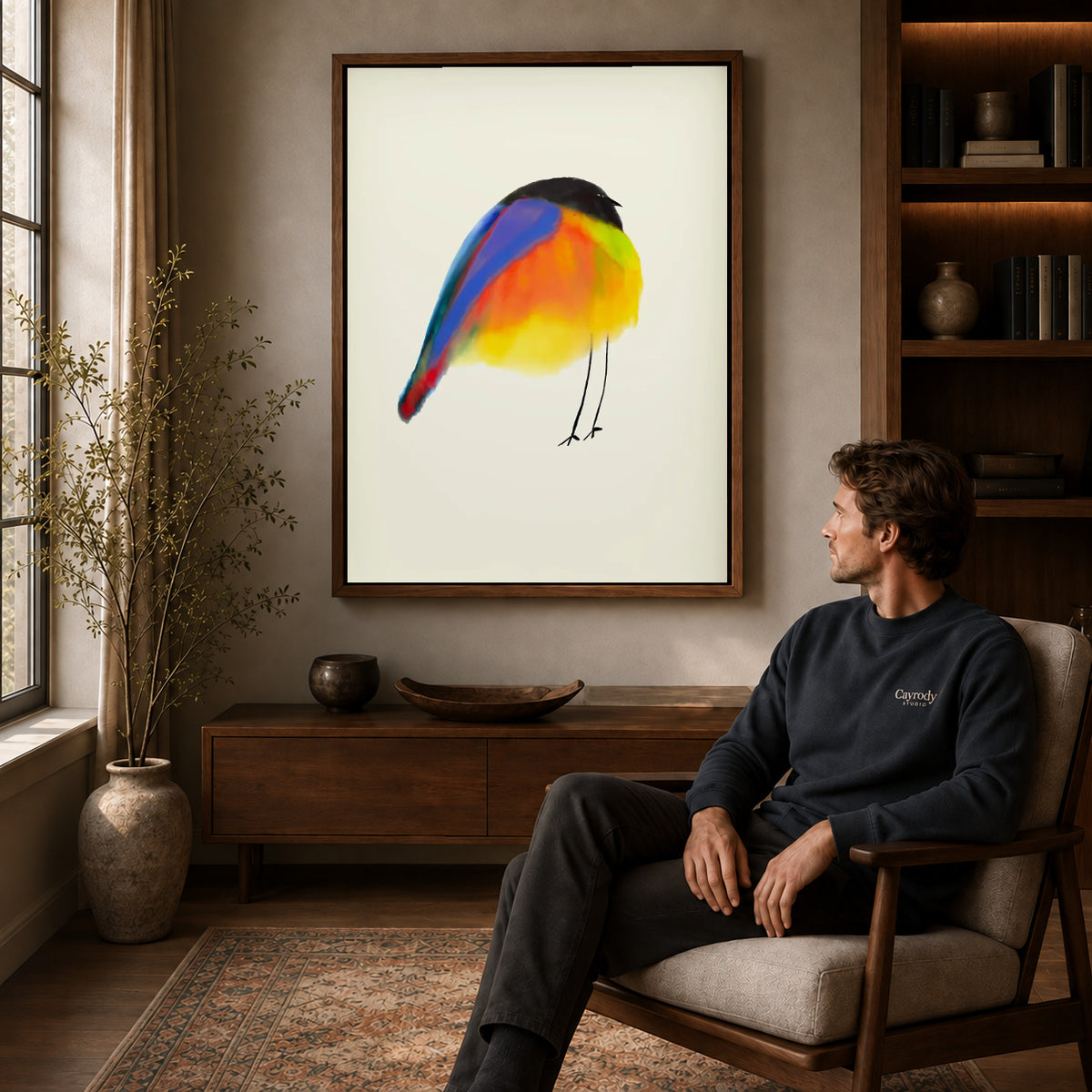 Colorful Bird canvas art above a wooden console beside a seated man in a warm room.