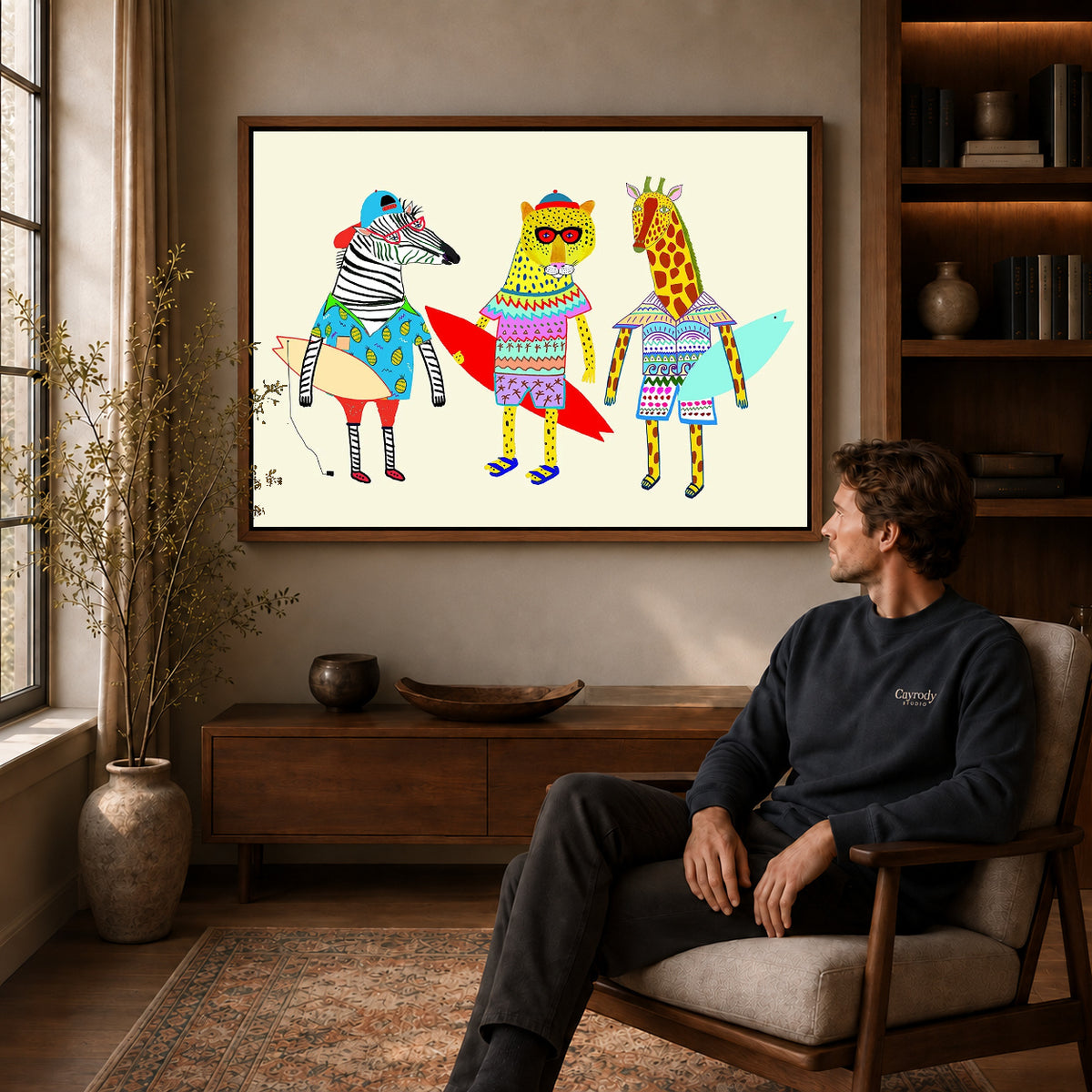 Surfing Animals canvas art above a wooden console beside a seated man in a warm room.