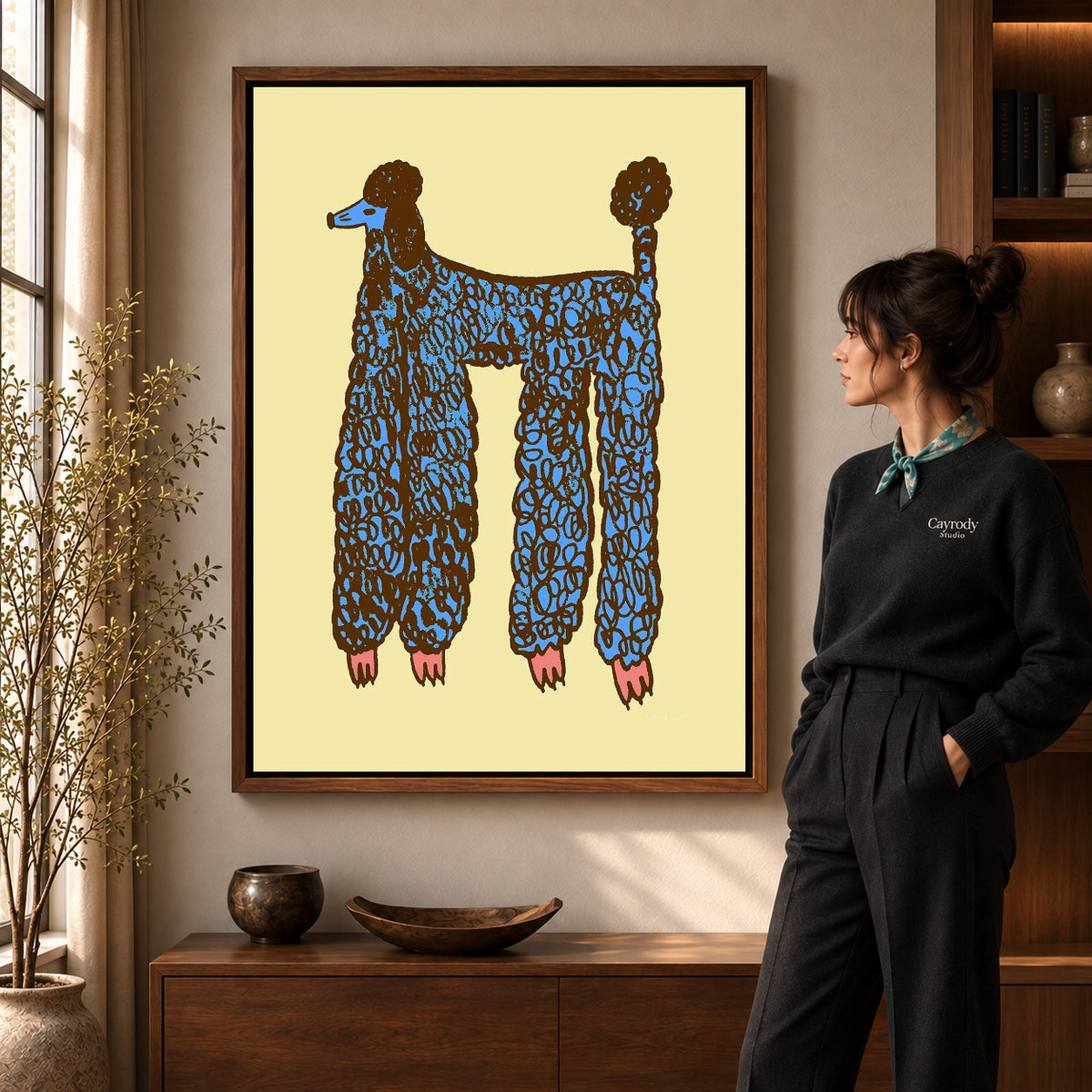 Walnut framed blue poodle canvas art shown beside a standing woman and a wooden console.