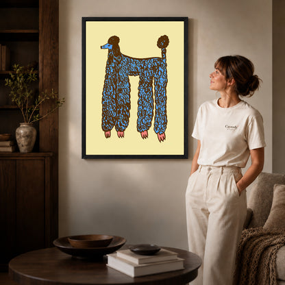 Black framed blue poodle canvas art displayed beside a woman in a warm living room.