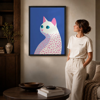 Black framed spotted cat canvas art displayed beside a woman in a warm living room.