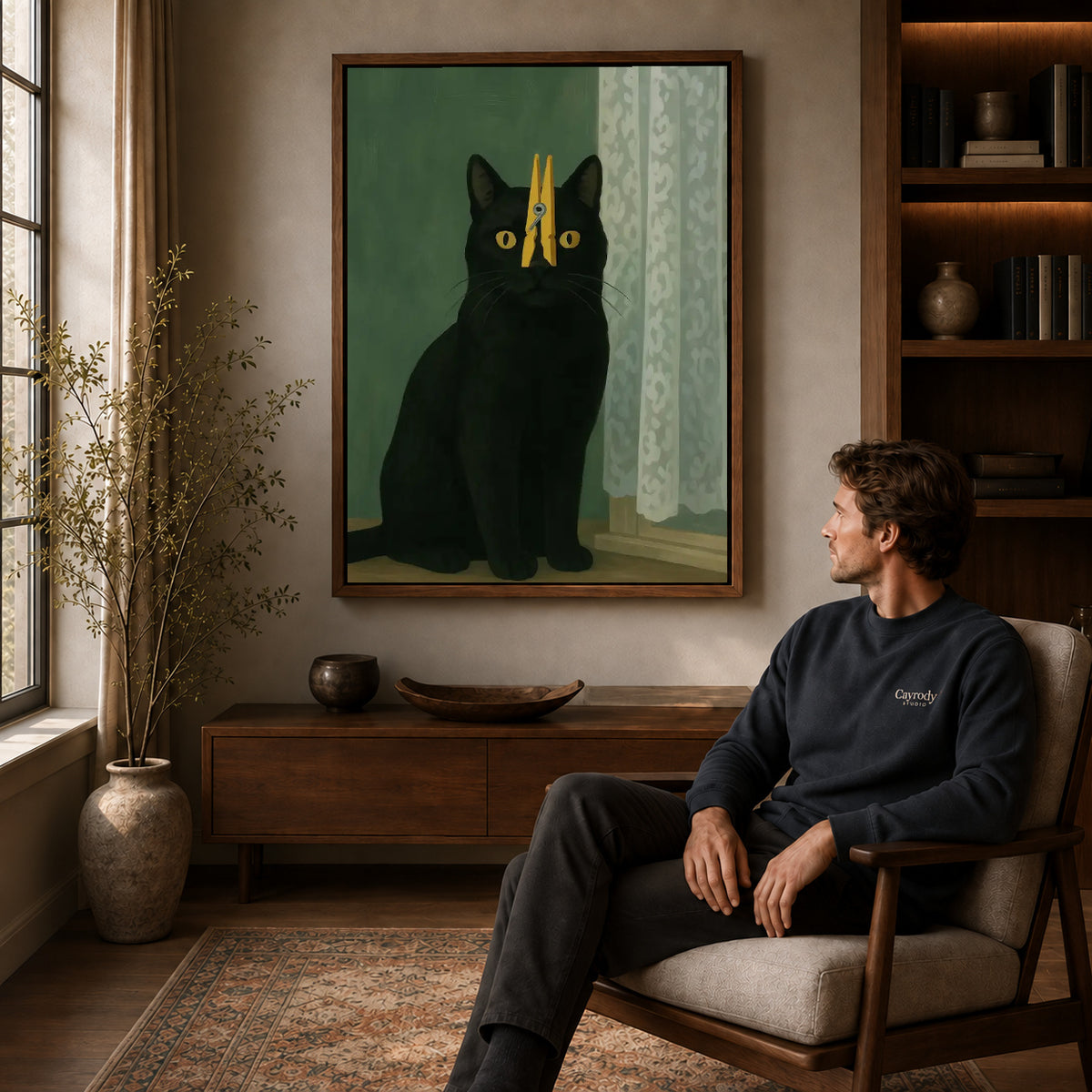 Clothespin Cat canvas art above a wooden console beside a seated man in a warm room.