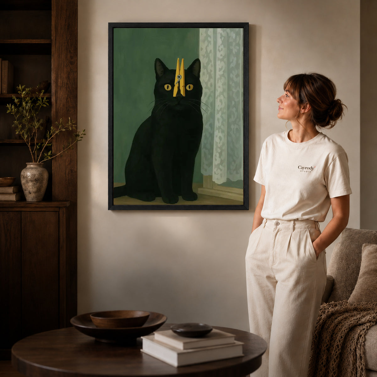 Clothespin Cat canvas art in a black frame above books in a welcoming living room.