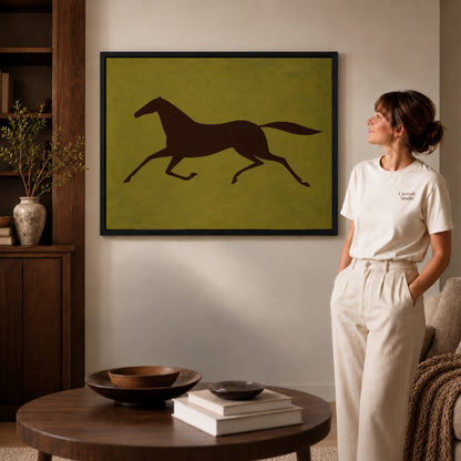 Galloping Horse canvas art in a black frame above books in a welcoming living room.