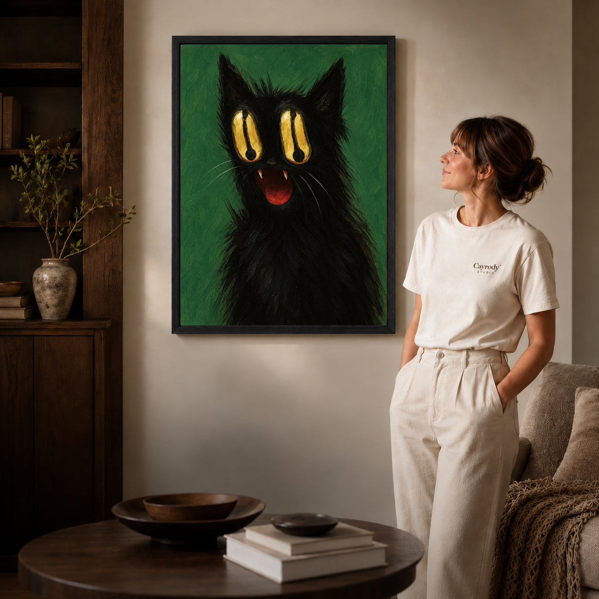 Black framed golden eyed cat canvas art displayed beside a woman in a warm living room.