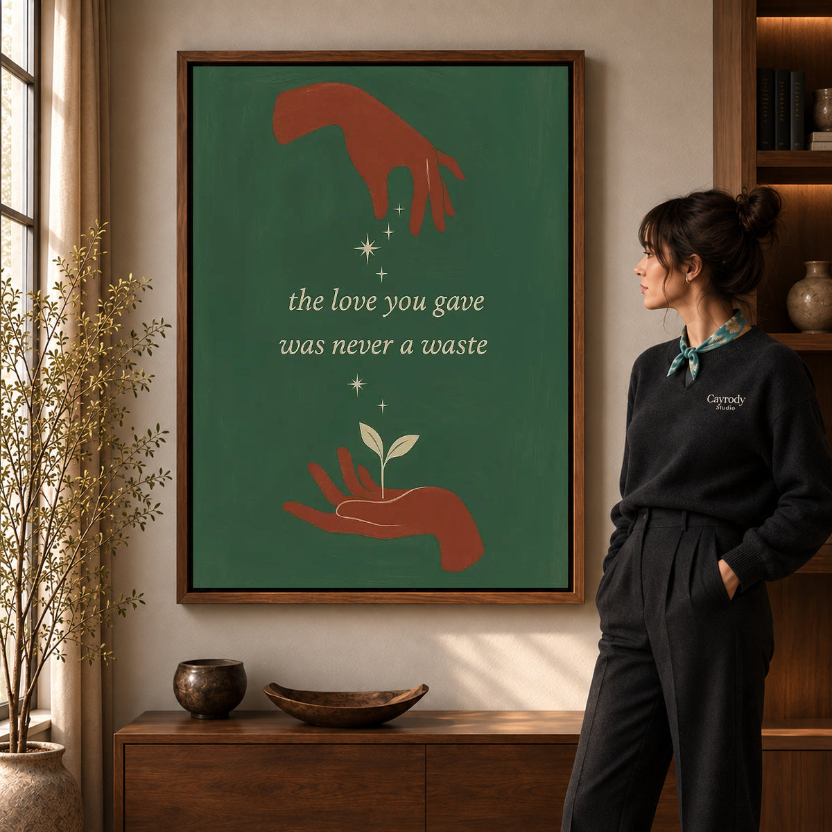 Growing Love canvas art in a walnut frame beside a standing woman and wooden console.