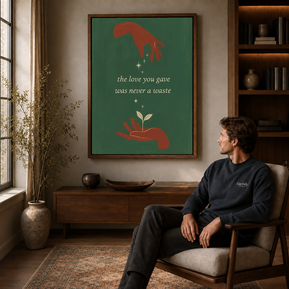 Growing Love canvas art above a wooden console beside a seated man in a warm room.