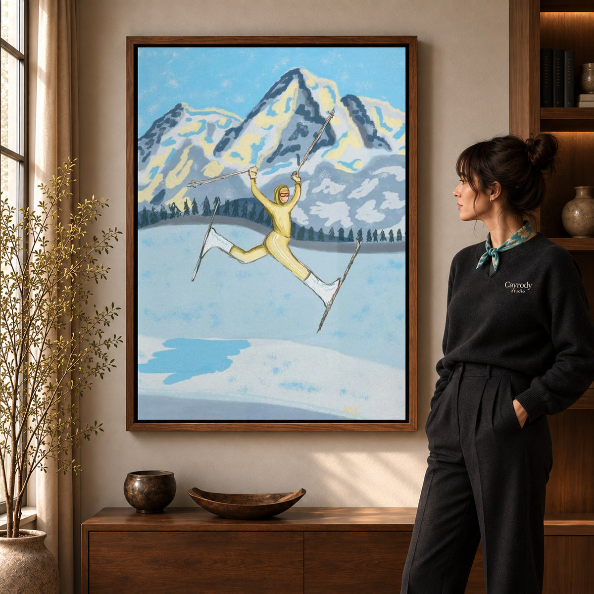 Walnut framed joyful skier canvas art shown beside a standing woman and a wooden console.