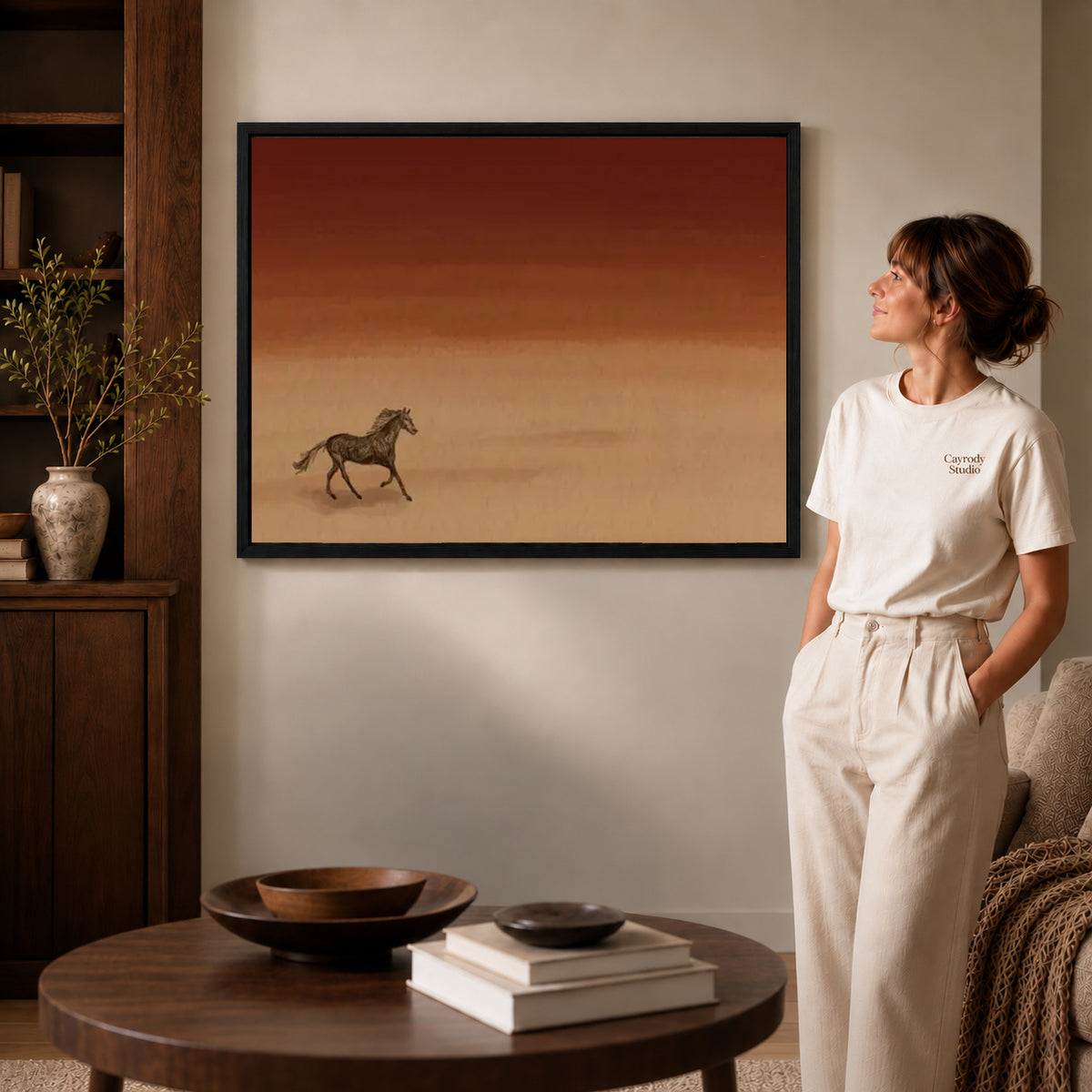 Desert Horse canvas art in a black frame above books in a welcoming living room.