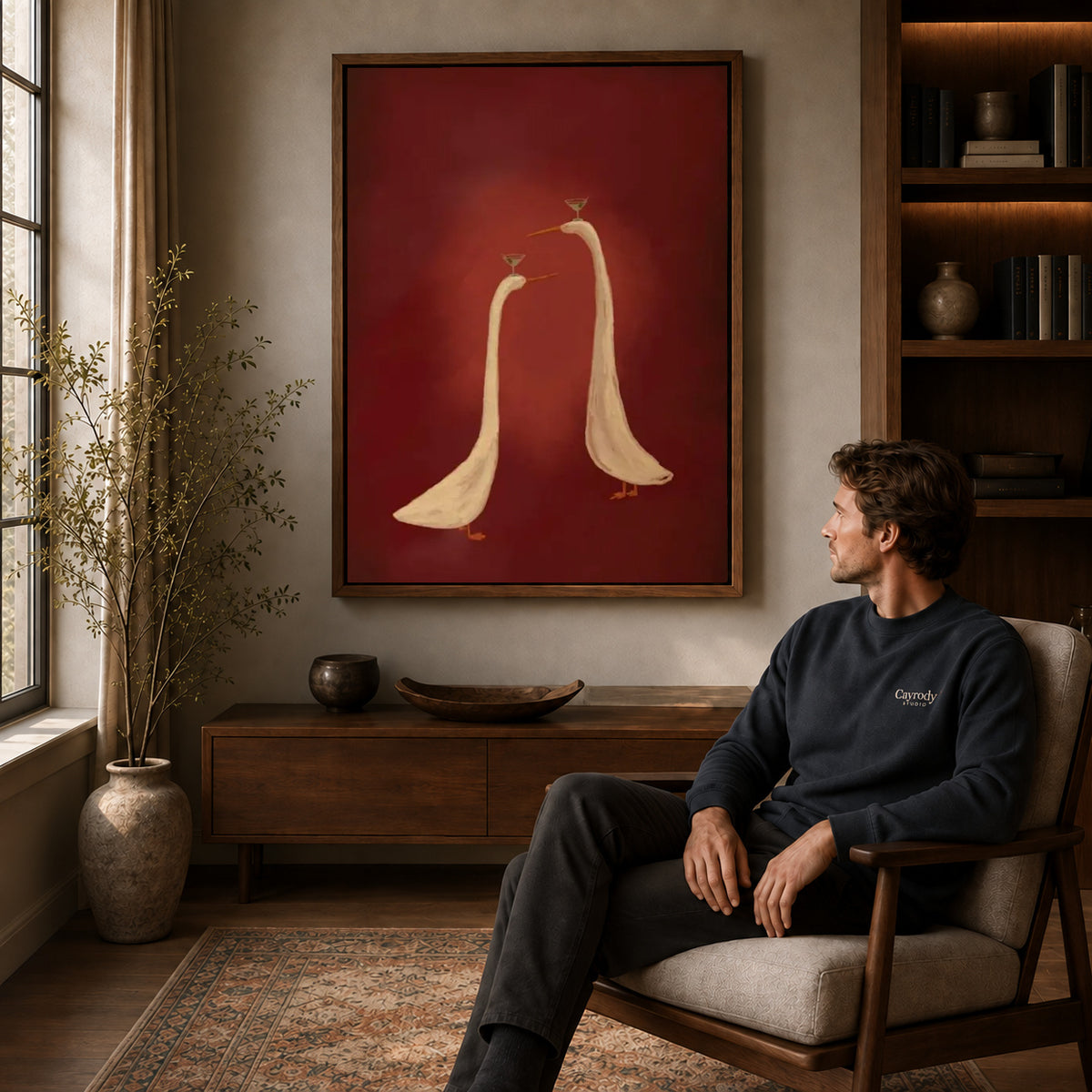 Cocktail Geese canvas art above a wooden console beside a seated man in a warm room.