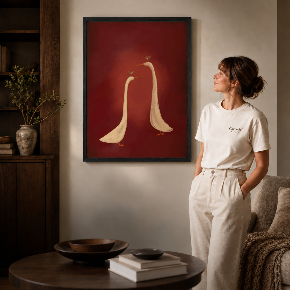 Cocktail Geese canvas art in a black frame above books in a welcoming living room.