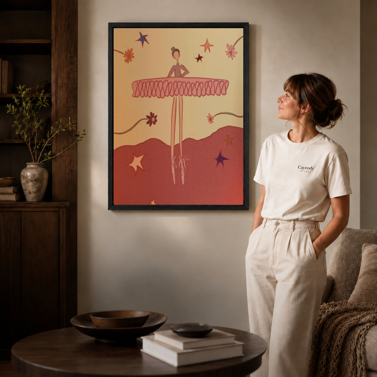 Playful Ballerina canvas art in a black frame above books in a welcoming living room.