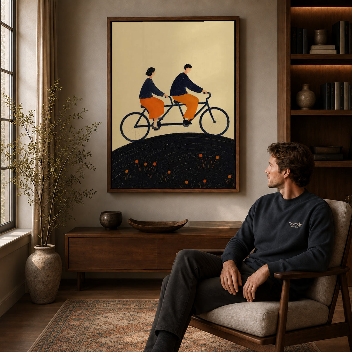 Tandem Ride canvas art above a wooden console beside a seated man in a warm room.