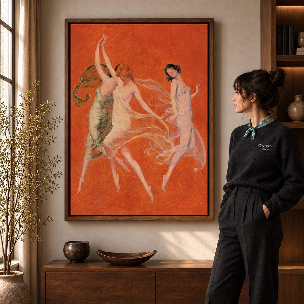 Walnut framed graceful dancers canvas art shown beside a standing woman and a wooden console.
