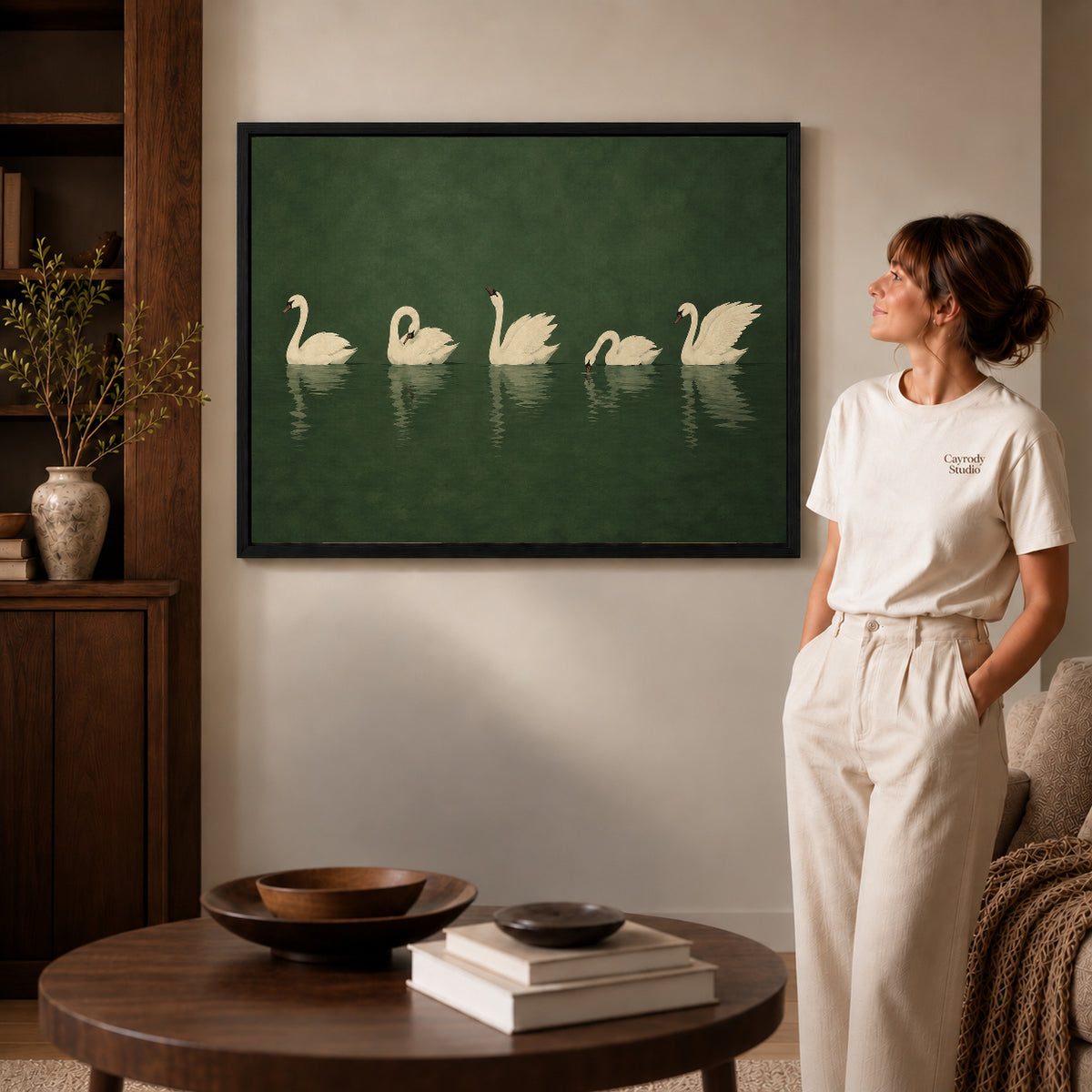Quiet Swan Gathering canvas art in a black frame above books in a welcoming living room.