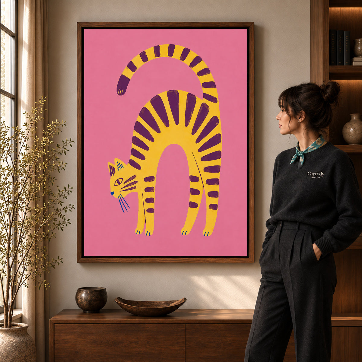 Arched Tabby canvas art in a walnut frame beside a standing woman and wooden console.