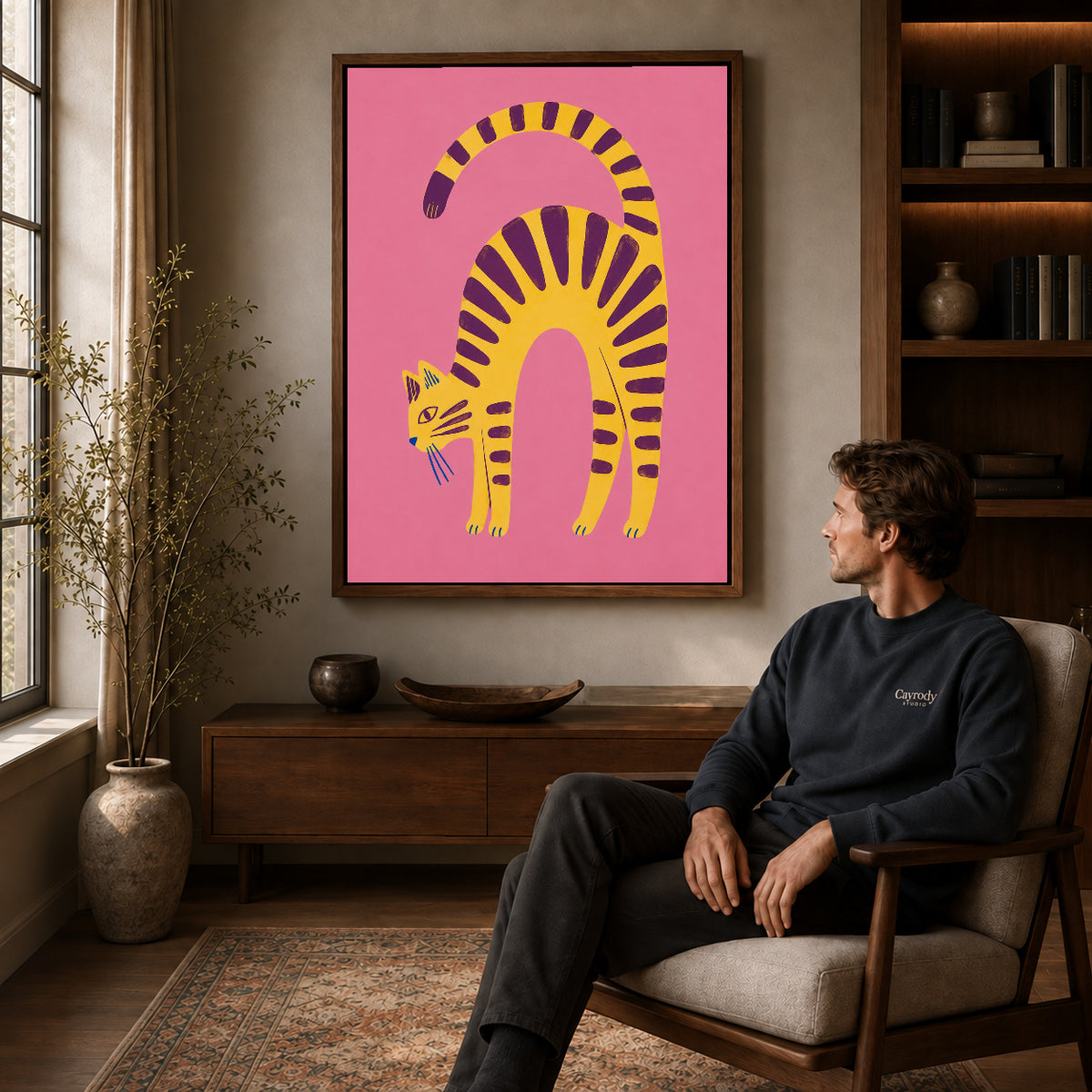 Arched Tabby canvas art above a wooden console beside a seated man in a warm room.