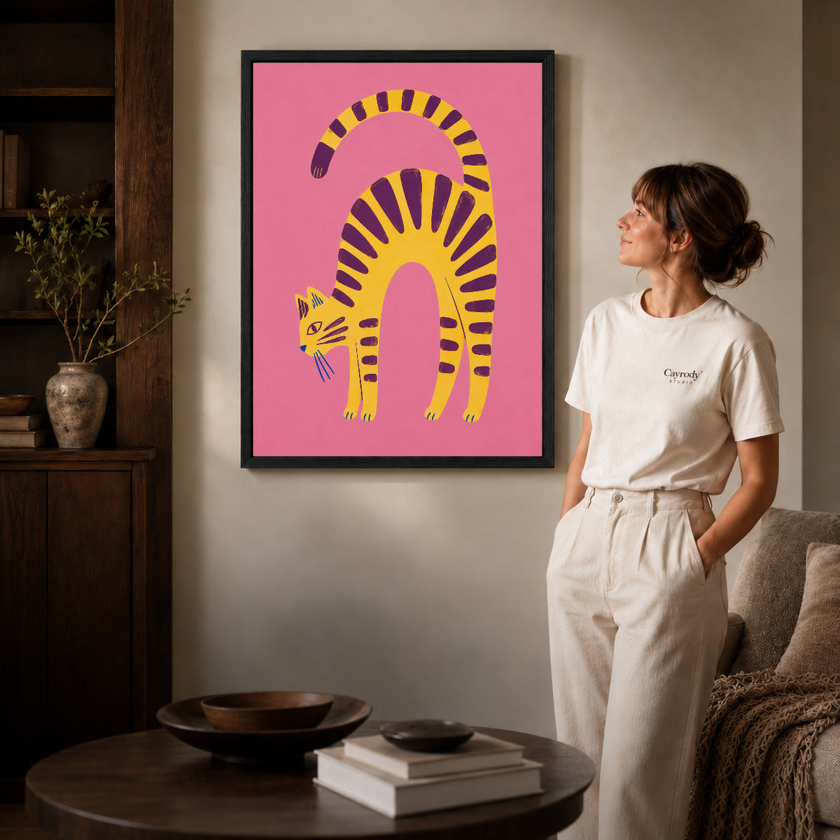 Arched Tabby canvas art in a black frame above books in a welcoming living room.