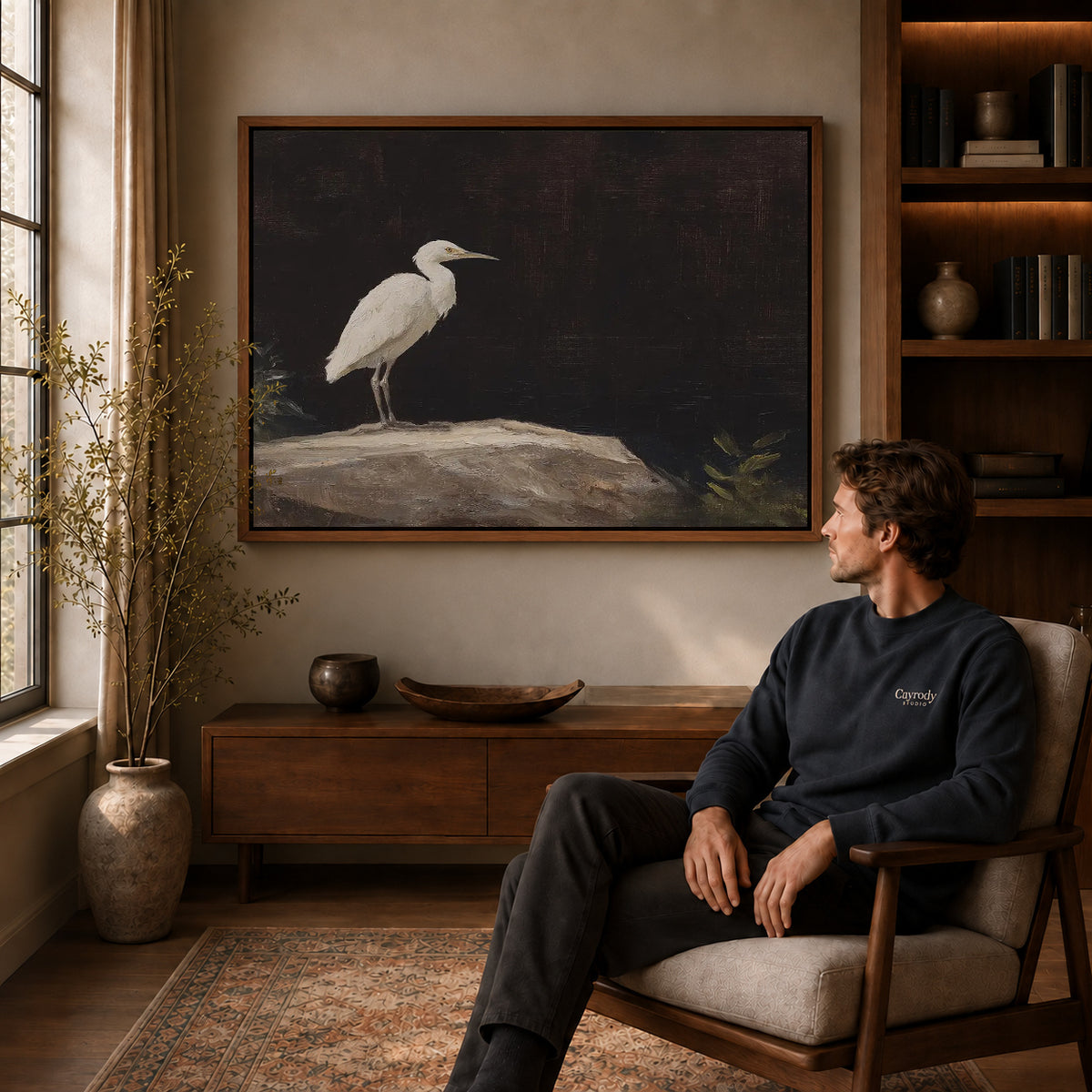 Quiet Egret canvas art above a wooden console beside a seated man in a warm room.