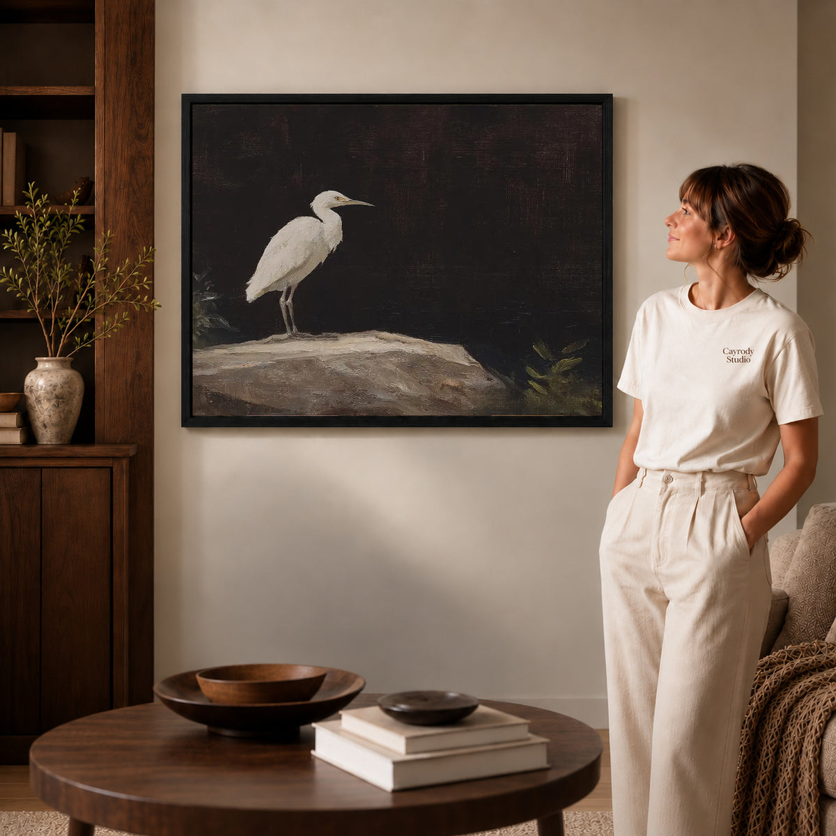 Quiet Egret canvas art in a black frame above books in a welcoming living room.
