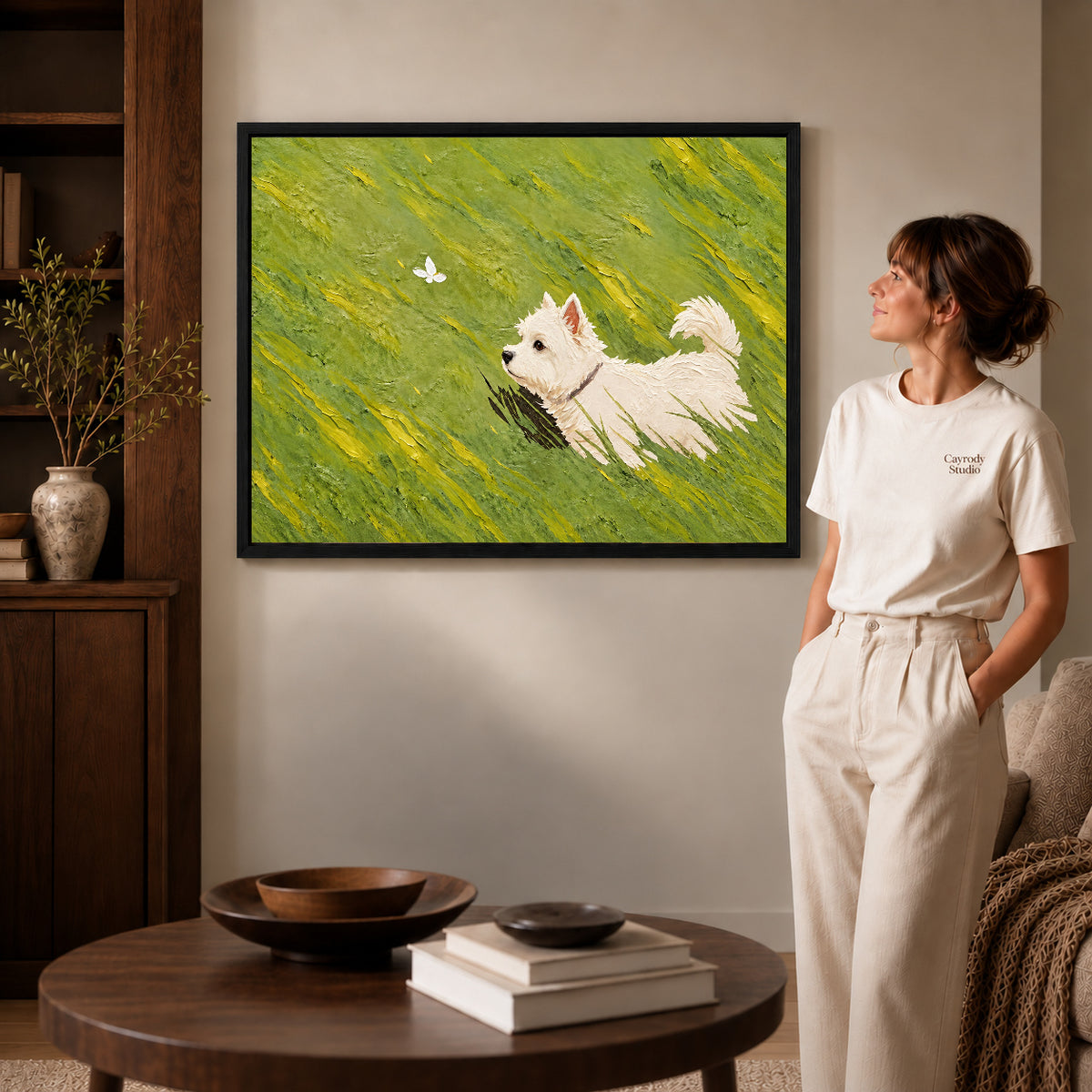 Westie Canvas Art inside a black frame in a softly lit living room with books.
