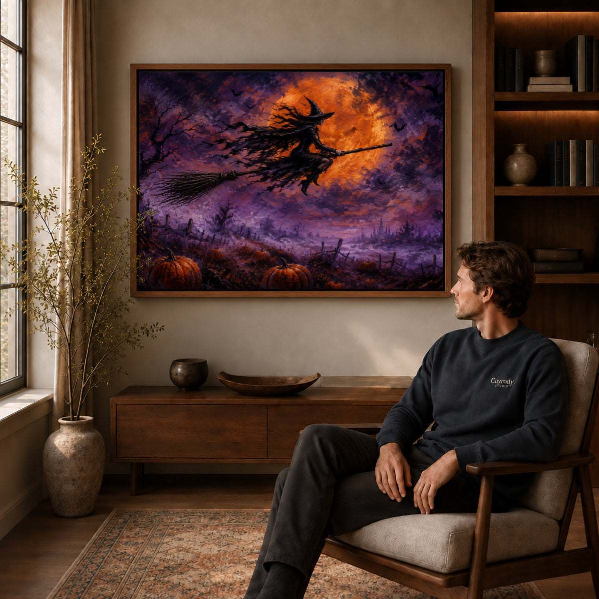 Witch Canvas Art displayed in a walnut frame above wooden furniture beside a seated man.