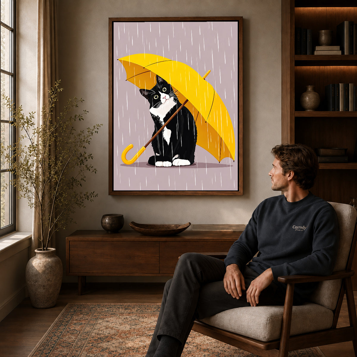 Umbrella Cat Canvas Art displayed in a walnut frame above wooden furniture beside a seated man.