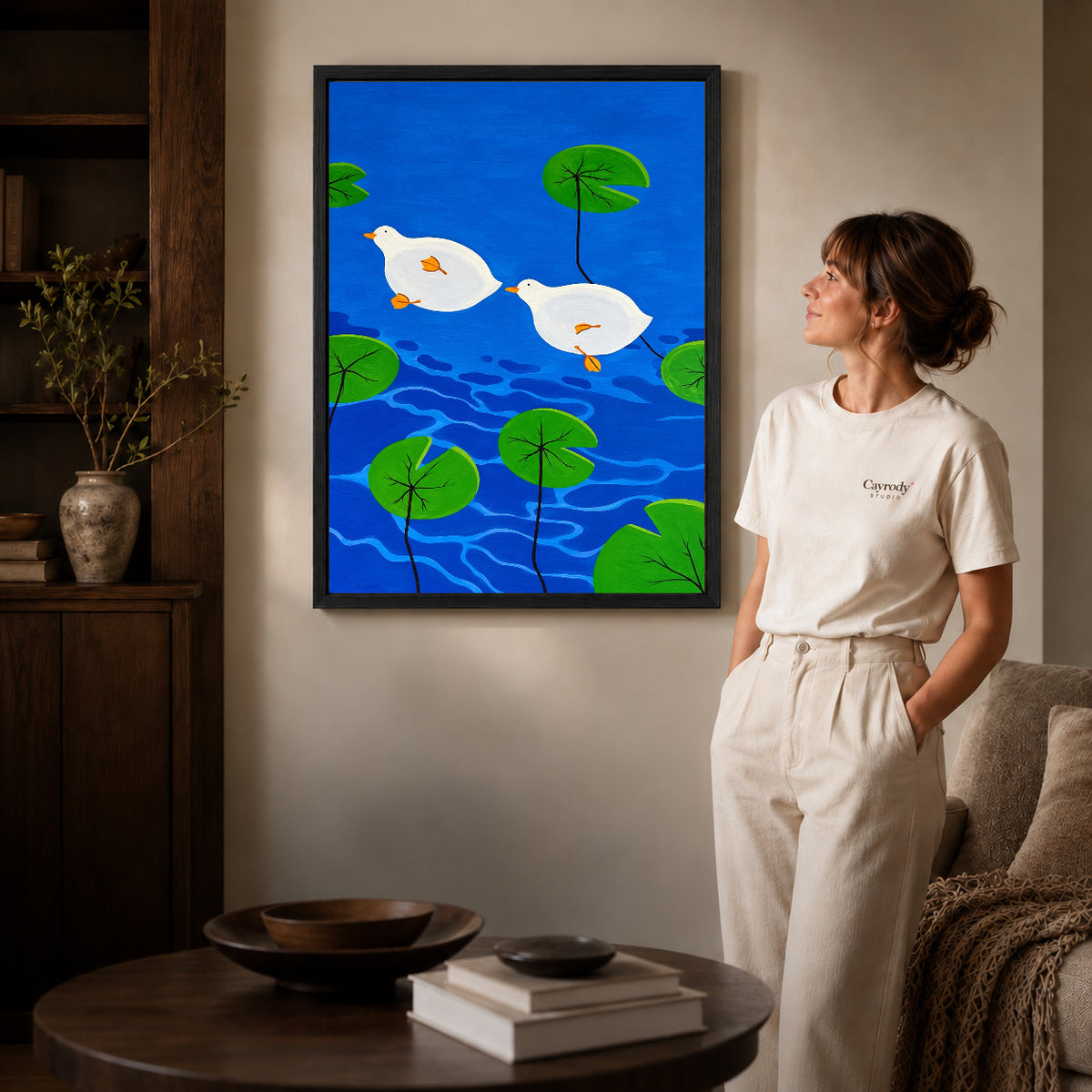 Black framed duck canvas art displayed beside a woman with natural light across the wall.
