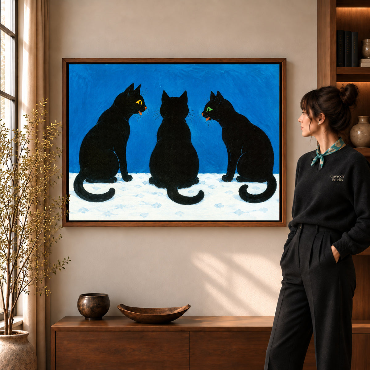 Black Cat Canvas Art in a walnut frame beside a standing woman and warm wooden furniture.