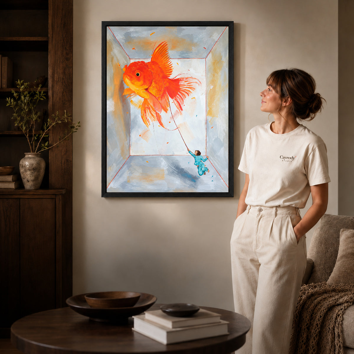 Goldfish Canvas Art inside a black frame in a softly lit living room with books.