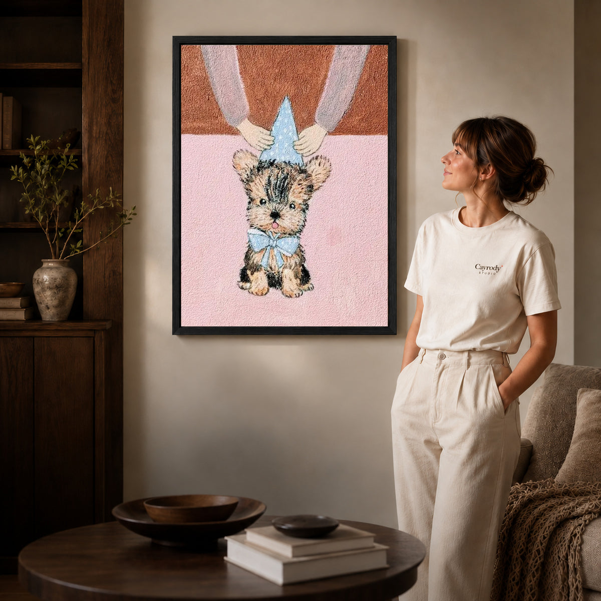 Birthday Puppy Canvas Art inside a black frame in a softly lit living room with books.