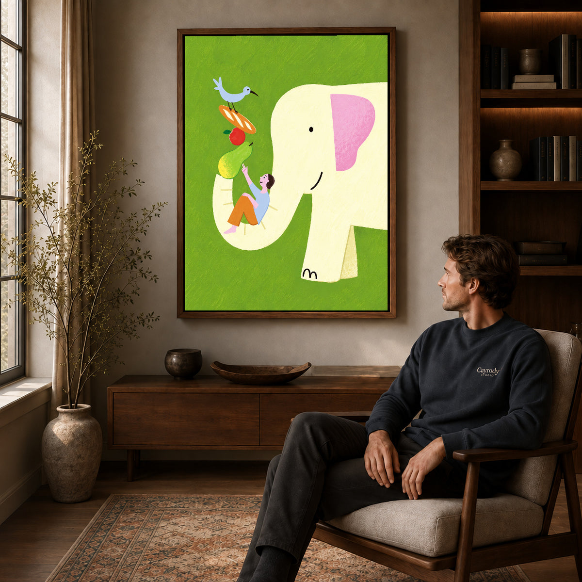Elephant Canvas Art displayed in a walnut frame above wooden furniture beside a seated man.