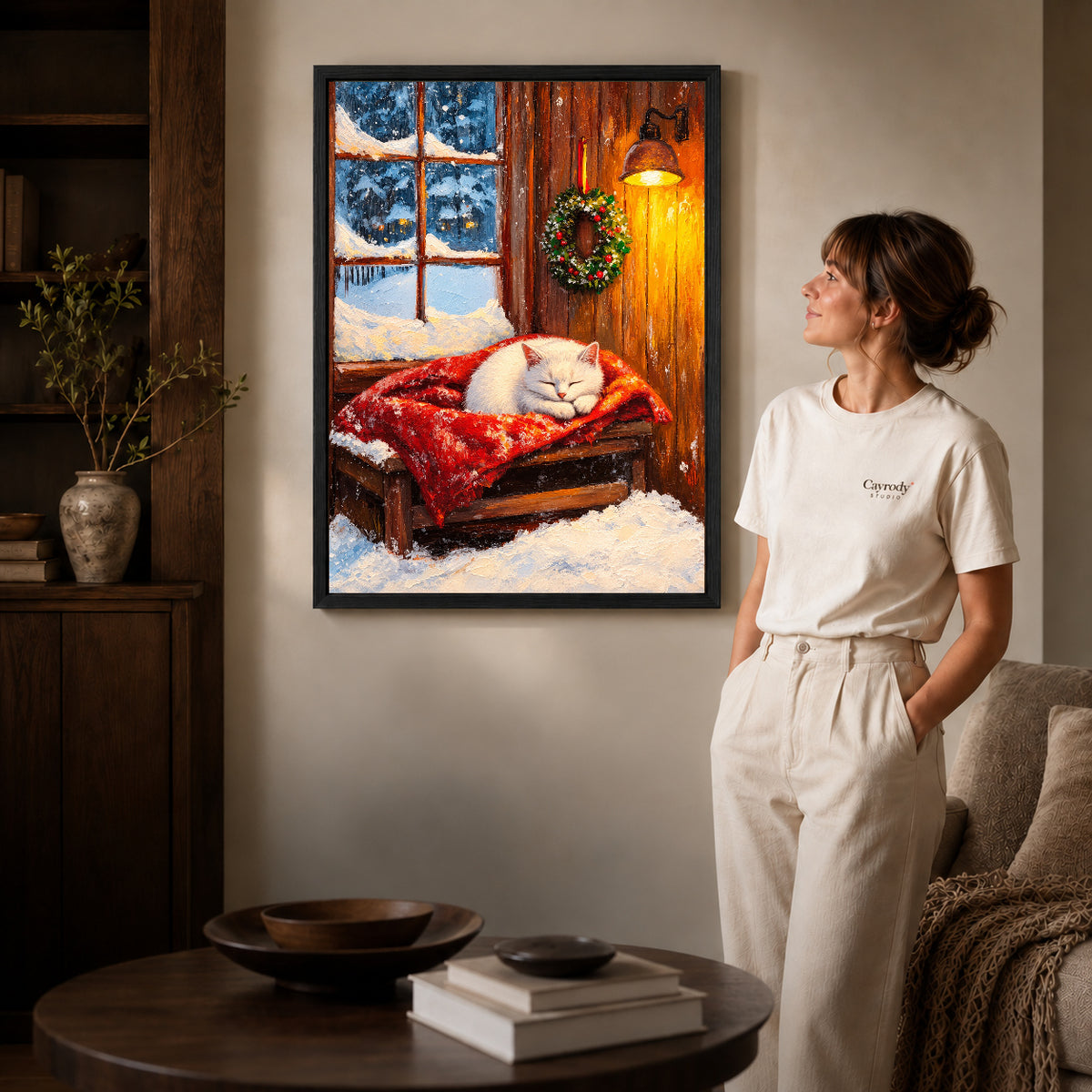 Winter Kitten Canvas Art inside a black frame in a softly lit living room with books.