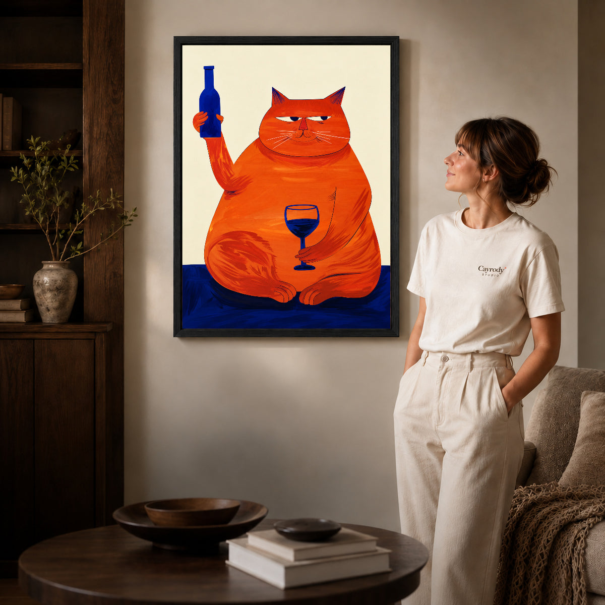 Black framed funny cat canvas art displayed beside a woman with natural light across the wall.