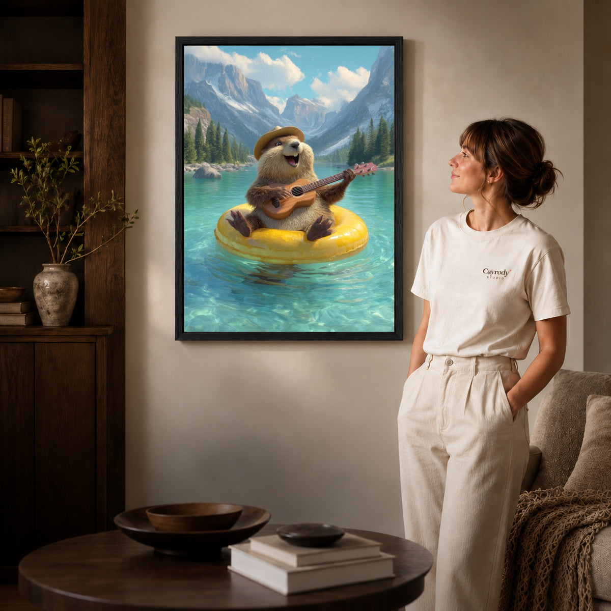 Otter Canvas Art inside a black frame in a softly lit living room with books.