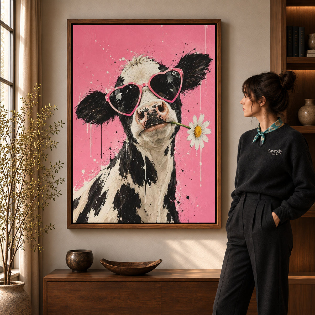 Funny Cow Canvas Art in a walnut frame beside a standing woman and warm wooden furniture.