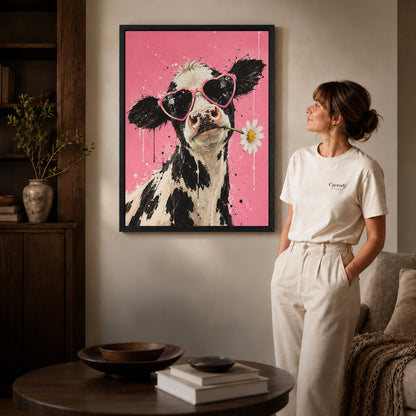 Black framed funny cow canvas art displayed beside a woman with natural light across the wall.