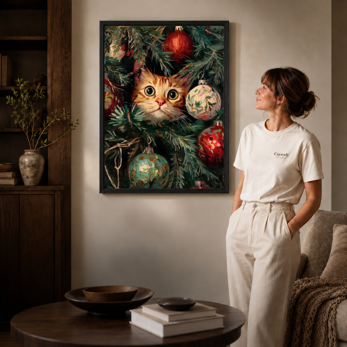 Christmas Kitten Canvas Art inside a black frame in a softly lit living room with books.