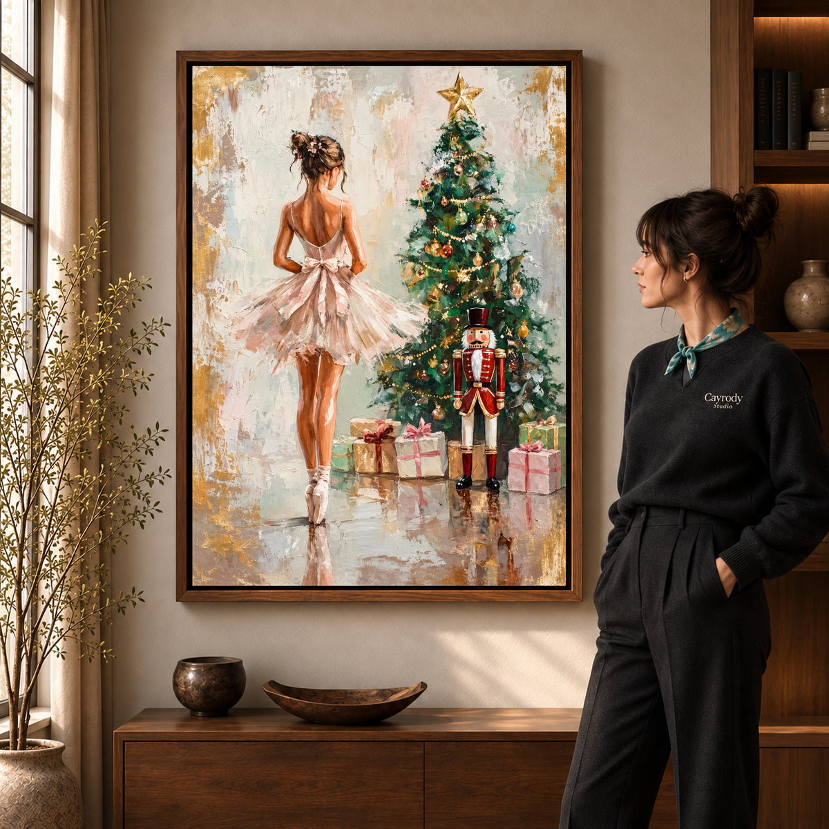 Christmas Ballet Canvas Art in a walnut frame beside a standing woman and warm wooden furniture.