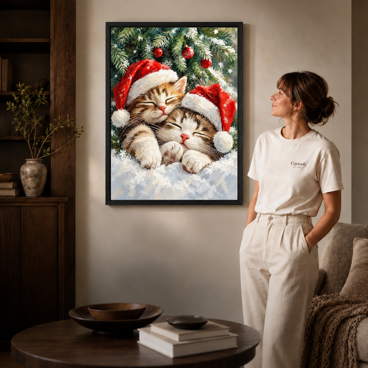 Black framed christmas kittens canvas art displayed beside a woman with natural light across the wall.