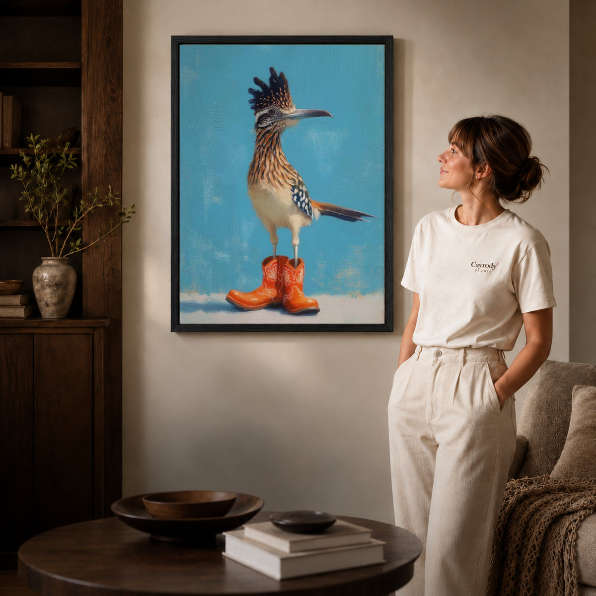 Roadrunner Canvas Art inside a black frame in a softly lit living room with books.
