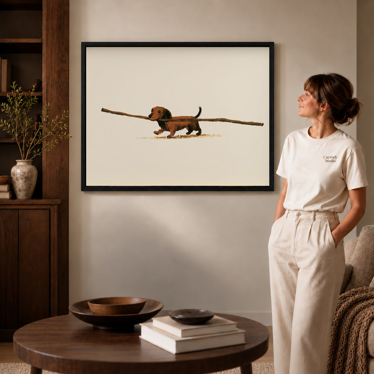 Dachshund Canvas Art inside a black frame in a softly lit living room with books.