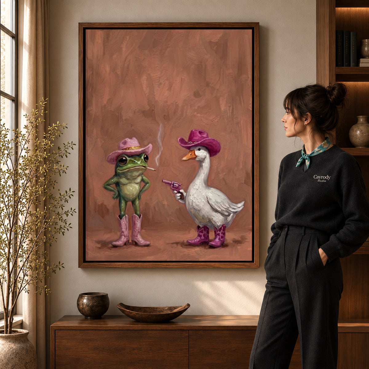 Frog Goose Canvas Art in a walnut frame beside a standing woman and warm wooden furniture.