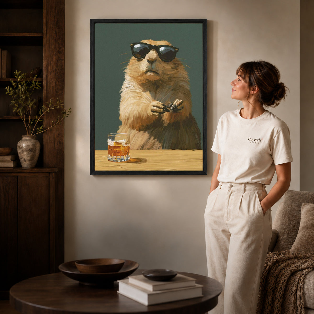 Marmot Canvas Art inside a black frame in a softly lit living room with books.