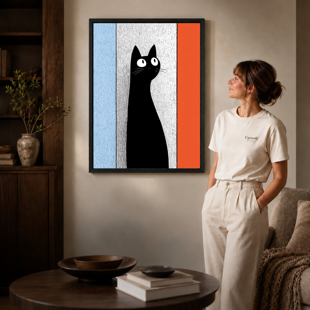 Black framed black cat canvas art displayed beside a woman with natural light across the wall.