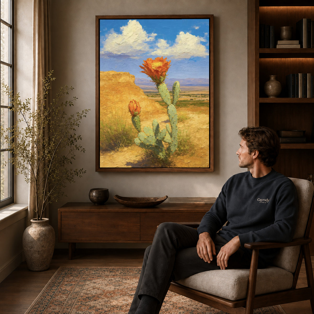 Cactus Canvas Art displayed in a walnut frame above wooden furniture beside a seated man.