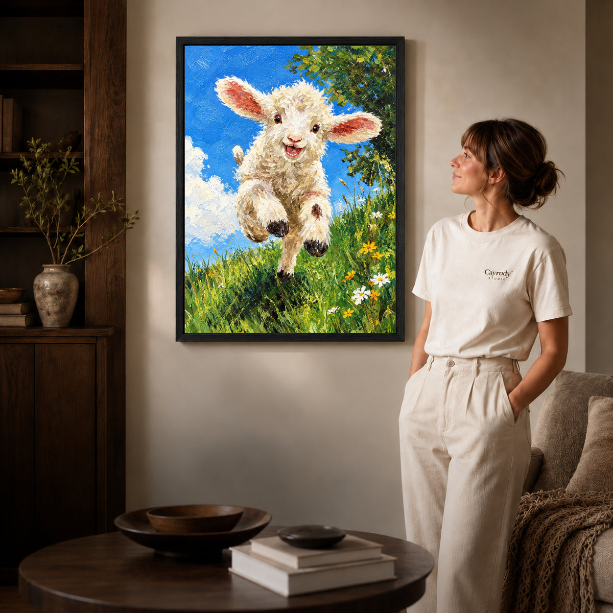 Lamb Canvas Art inside a black frame in a softly lit living room with books.